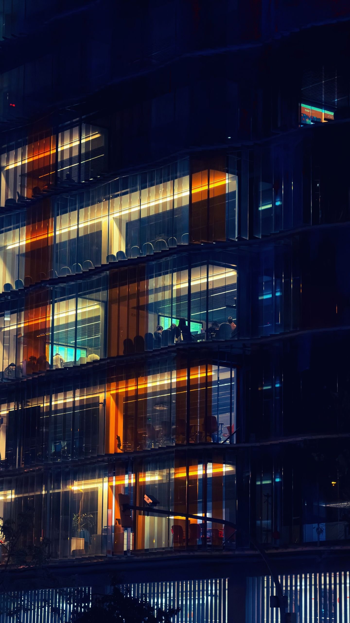 A modern office building glowing at night with bright interior lights in Barcelona, Spain.