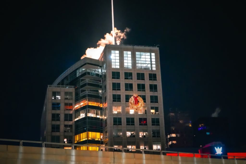 A tall building illuminated at night with a large holiday wreath displayed on its facade.