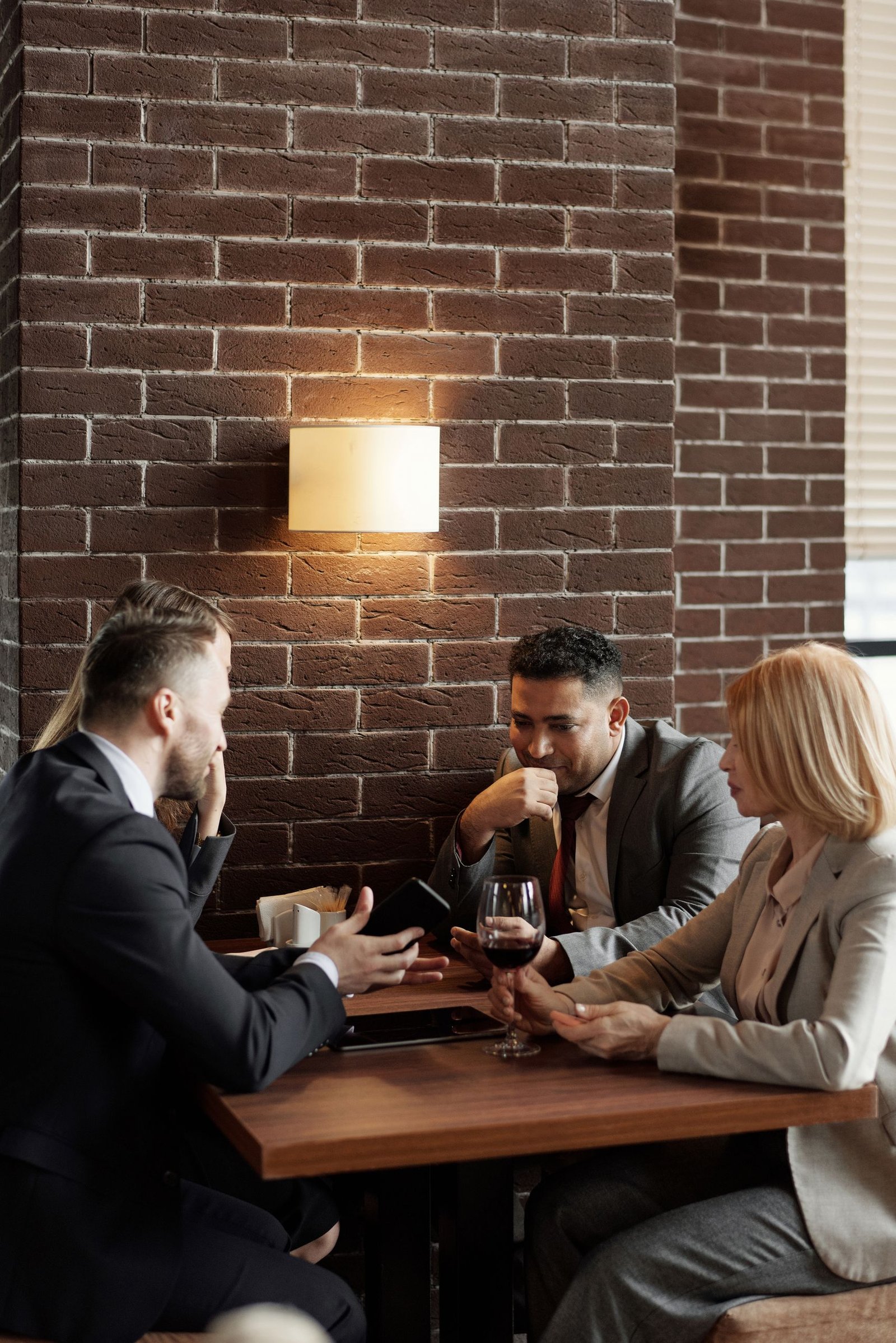 Business professionals discuss strategies over coffee and wine in a modern café setting.