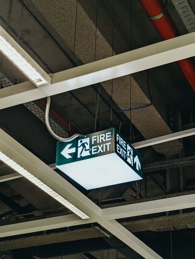 Close-up of a fire exit sign in an industrial ceiling structure, providing guidance for emergency exits.