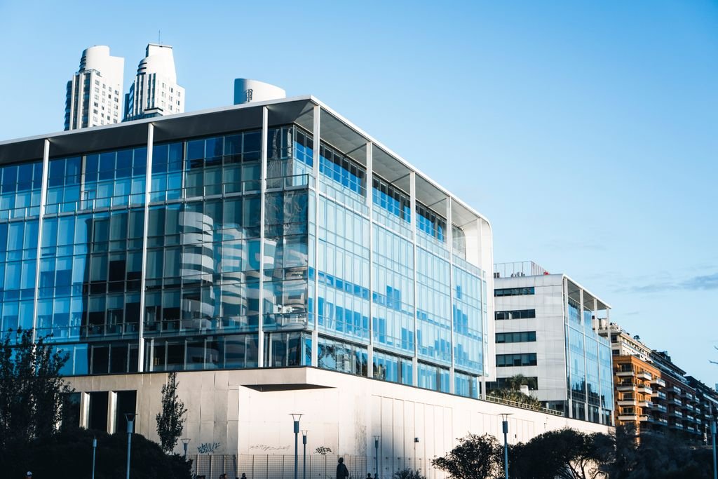 Low-angle view of a modern glass facade building in Buenos Aires' vibrant urban landscape.